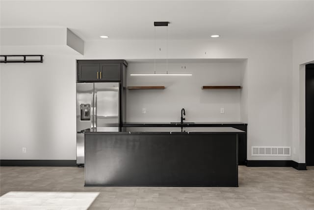 kitchen with hanging light fixtures, sink, stainless steel fridge with ice dispenser, and a kitchen island