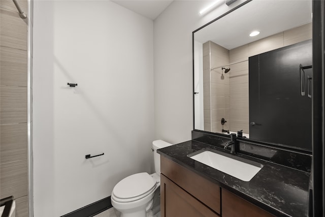 bathroom with tiled shower, vanity, and toilet