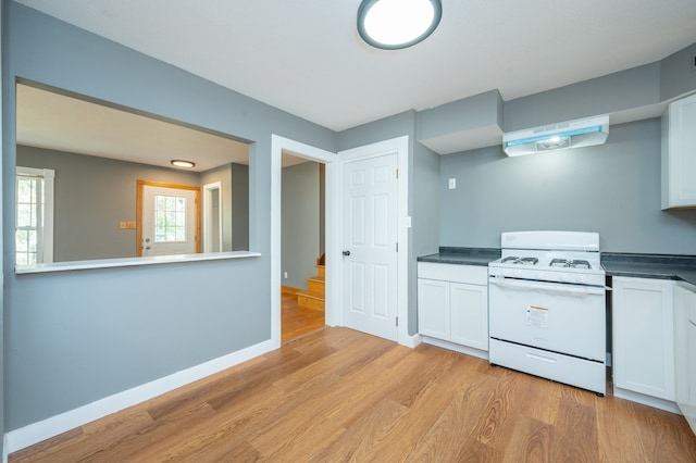 kitchen featuring white cabinets, light hardwood / wood-style flooring, extractor fan, and white gas range