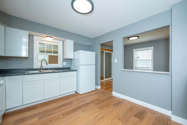 kitchen with light hardwood / wood-style flooring, white cabinetry, plenty of natural light, and white fridge