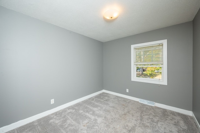 carpeted spare room featuring a textured ceiling