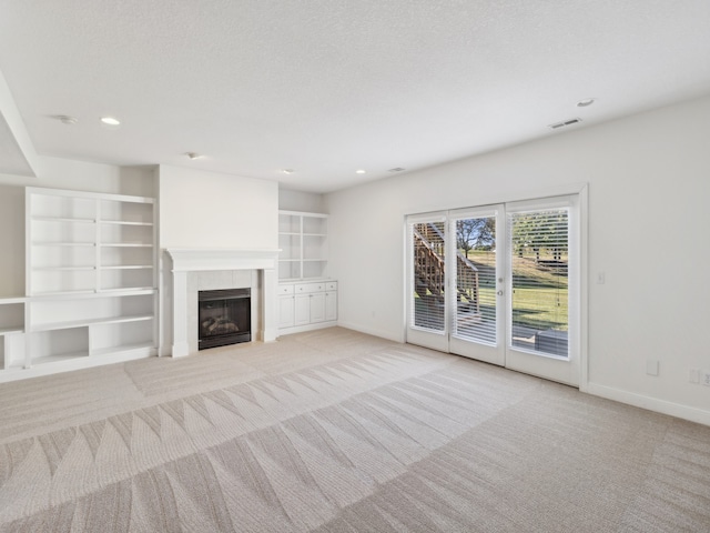 unfurnished living room with light carpet, a textured ceiling, and a tiled fireplace