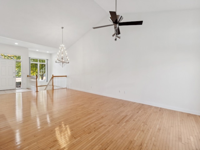 unfurnished room featuring high vaulted ceiling, light wood-type flooring, and ceiling fan with notable chandelier