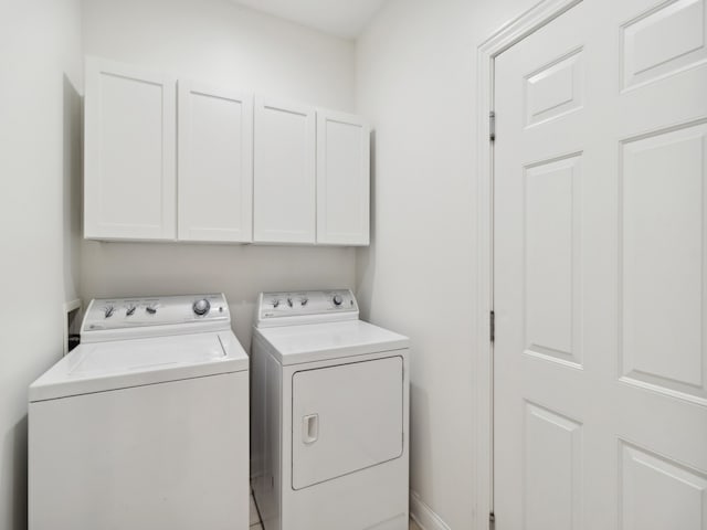 clothes washing area with cabinets and washer and clothes dryer