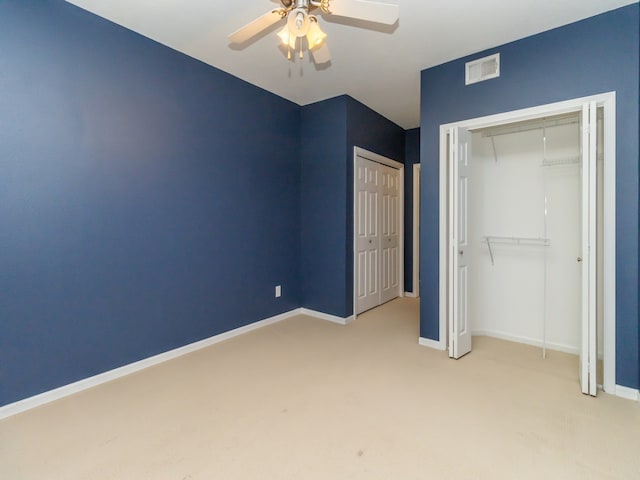 unfurnished bedroom with light carpet, ceiling fan, and multiple closets