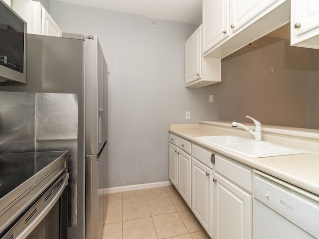 kitchen featuring stainless steel appliances, sink, light tile patterned floors, and white cabinetry