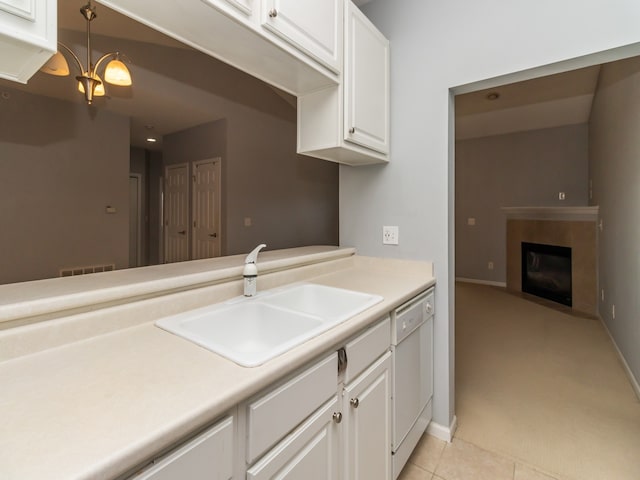 kitchen with a tile fireplace, decorative light fixtures, dishwasher, white cabinets, and light tile patterned floors