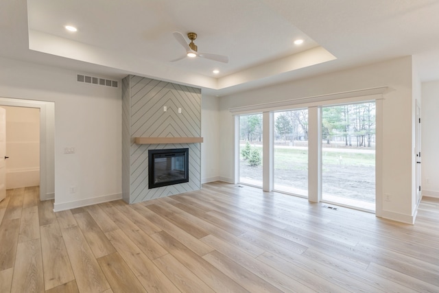 unfurnished living room featuring a fireplace, light wood-type flooring, and ceiling fan