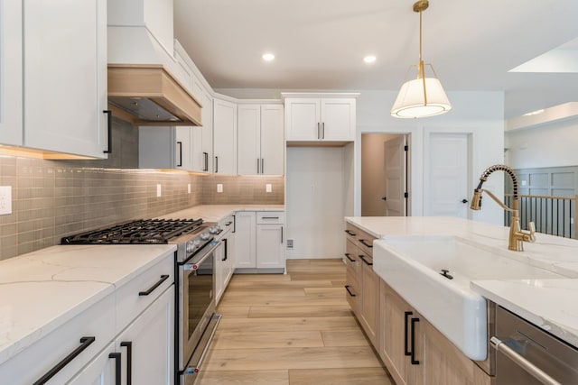 kitchen featuring white cabinetry, sink, pendant lighting, appliances with stainless steel finishes, and light wood-type flooring