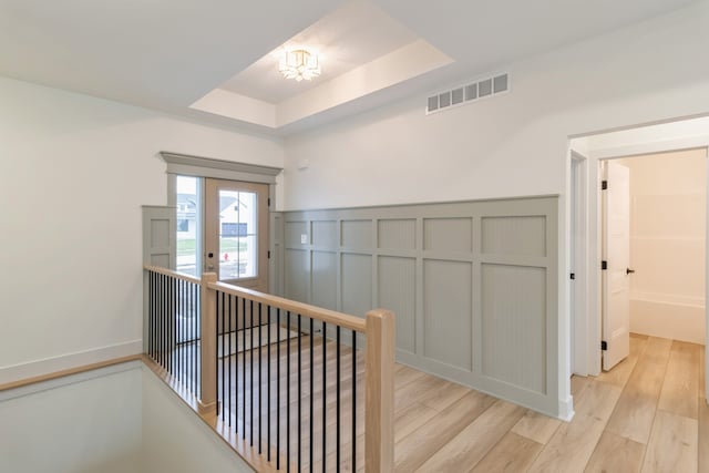 hallway featuring a raised ceiling and light hardwood / wood-style flooring