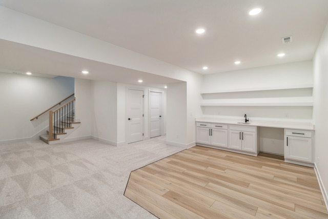 bar featuring white cabinets, light hardwood / wood-style floors, and sink