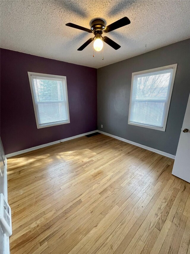 5711 Franklin Ave, Des Moines, IA 50310 - spare room with healthy amount of natural light, light wood-style flooring, a textured ceiling, ceiling fan, and baseboards