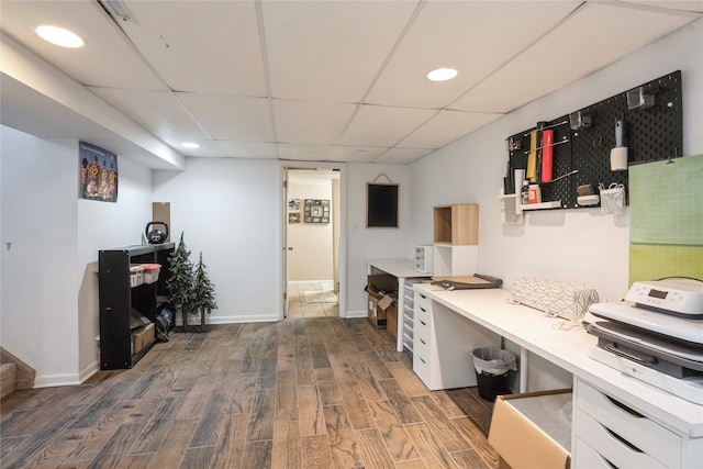 home office with dark wood-type flooring and a paneled ceiling