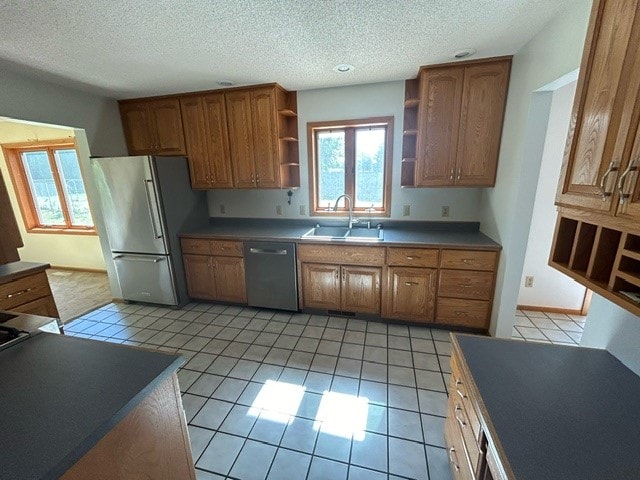 kitchen featuring light tile patterned flooring, appliances with stainless steel finishes, sink, and a textured ceiling