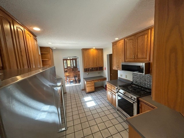 kitchen with a textured ceiling, appliances with stainless steel finishes, and light tile patterned floors