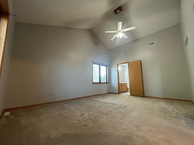 carpeted spare room featuring ceiling fan and high vaulted ceiling