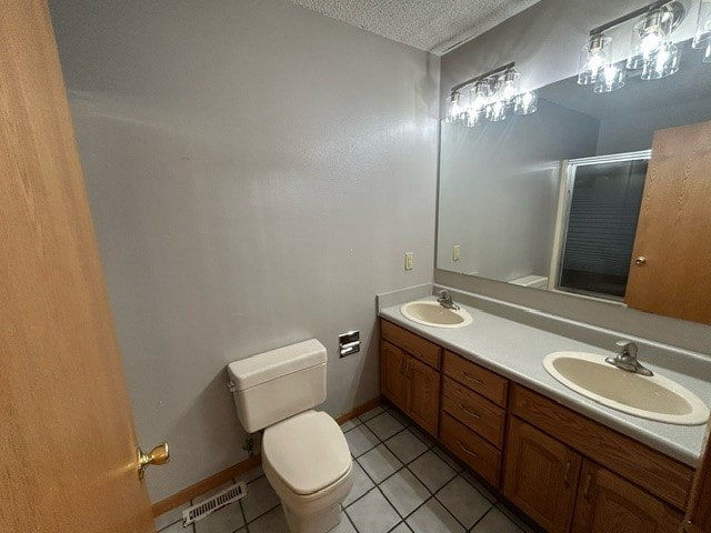 bathroom with vanity, an enclosed shower, a textured ceiling, tile patterned floors, and toilet