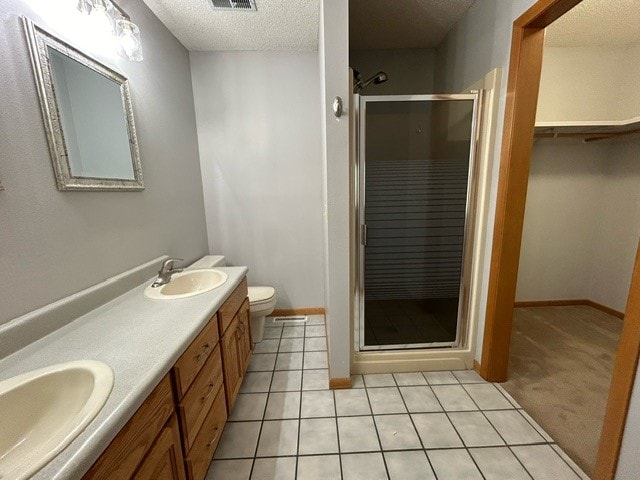 bathroom featuring a textured ceiling, tile patterned floors, a shower with shower door, vanity, and toilet