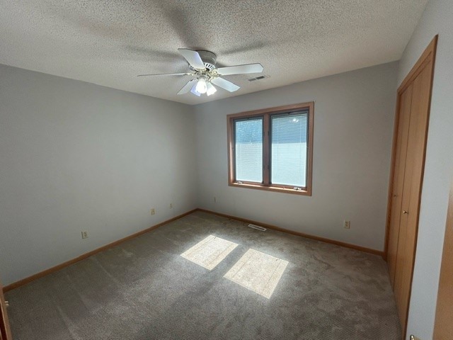 unfurnished bedroom featuring a textured ceiling, carpet flooring, and ceiling fan