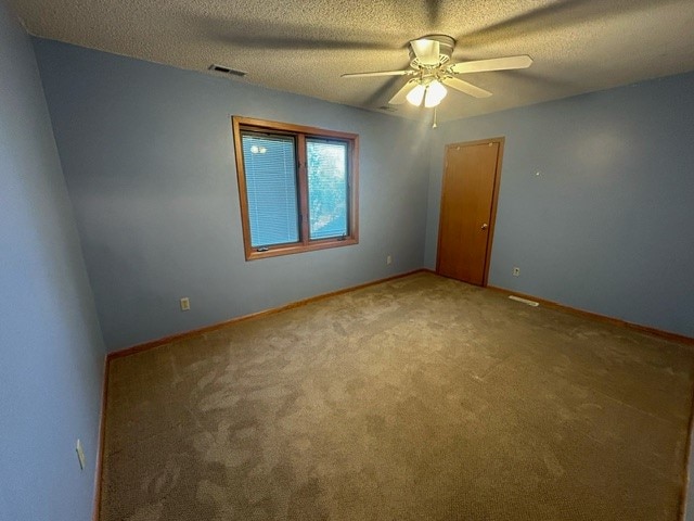 empty room featuring ceiling fan, carpet floors, and a textured ceiling