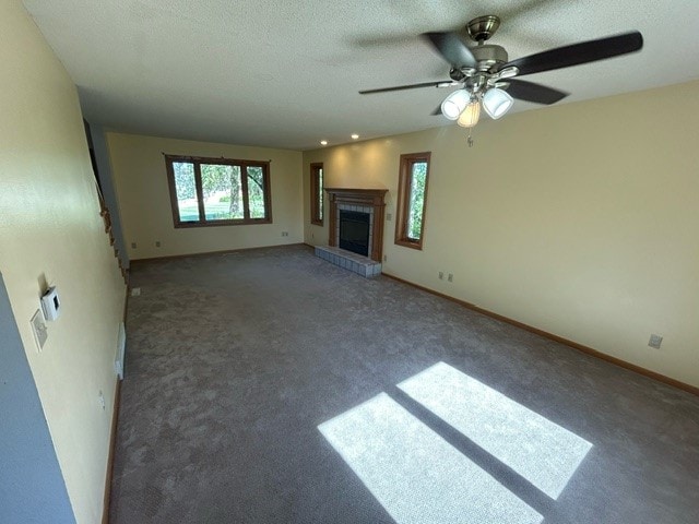 unfurnished living room featuring a textured ceiling, ceiling fan, and dark carpet