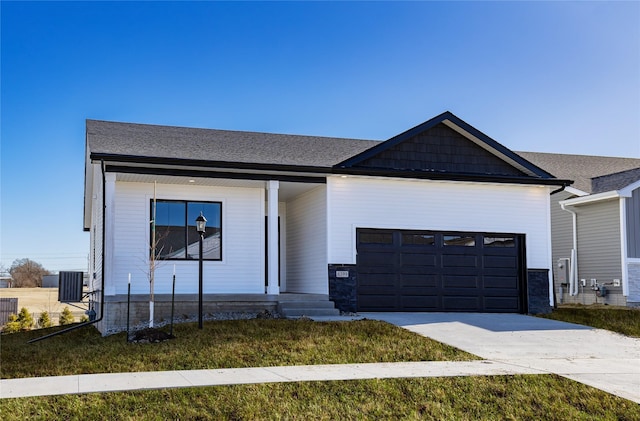 view of front facade with a garage, a front lawn, and central air condition unit