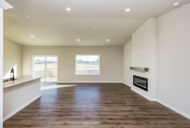 unfurnished living room featuring sink and dark hardwood / wood-style floors