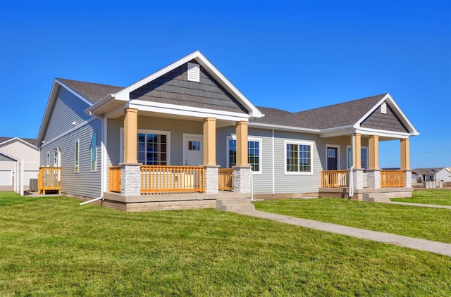 craftsman house with central AC, a porch, a front lawn, and roof with shingles