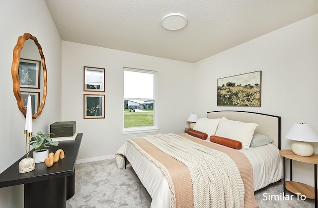 bedroom featuring light colored carpet and a textured ceiling