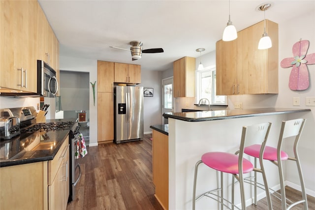 kitchen with pendant lighting, dark hardwood / wood-style floors, a kitchen bar, stainless steel appliances, and light brown cabinetry