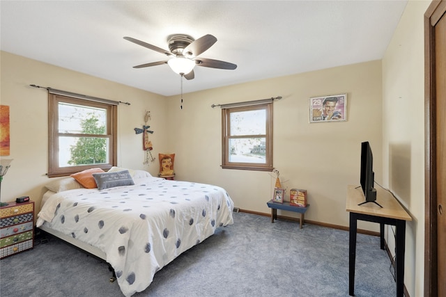 bedroom featuring ceiling fan, dark colored carpet, and multiple windows