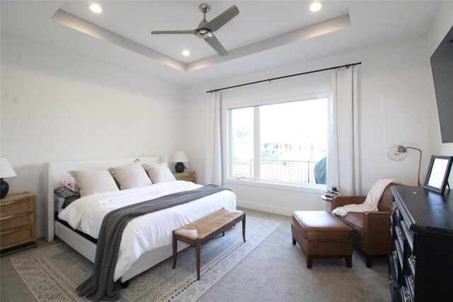 carpeted bedroom featuring ceiling fan and a raised ceiling