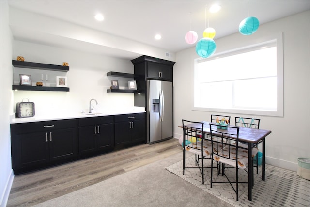 kitchen featuring sink, stainless steel fridge, pendant lighting, and light wood-type flooring