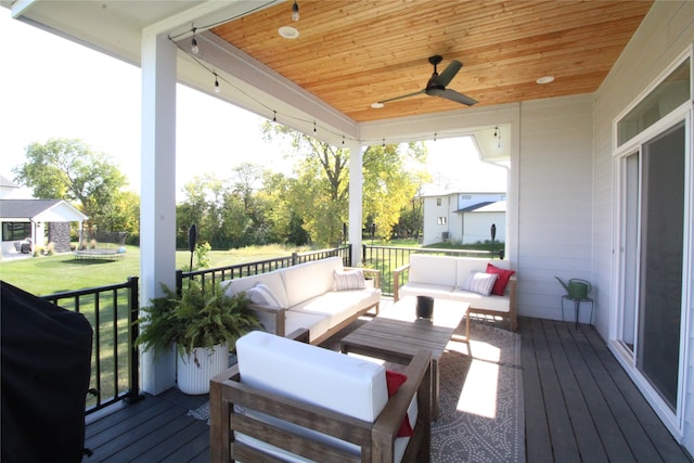 wooden terrace with grilling area, ceiling fan, a lawn, and an outdoor hangout area