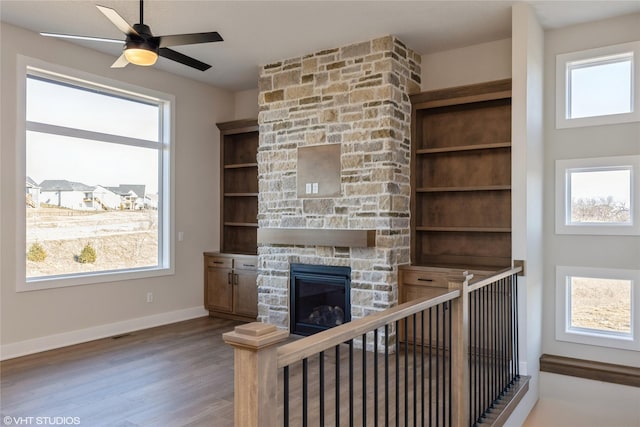 unfurnished living room with hardwood / wood-style floors, plenty of natural light, built in features, and a fireplace