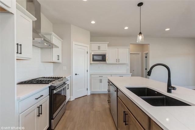 kitchen featuring backsplash, sink, wall chimney exhaust hood, appliances with stainless steel finishes, and white cabinetry