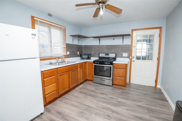 kitchen with tasteful backsplash, sink, light hardwood / wood-style flooring, stainless steel gas range, and white refrigerator