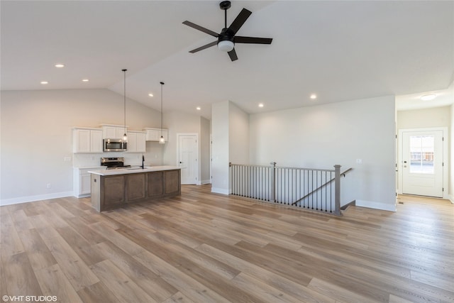 unfurnished living room featuring lofted ceiling, light wood-type flooring, ceiling fan, and sink