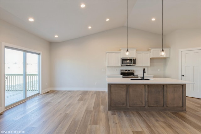 kitchen with stainless steel appliances, sink, white cabinetry, light hardwood / wood-style floors, and a center island with sink