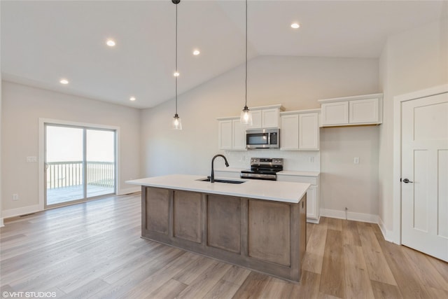 kitchen featuring white cabinets, a kitchen island with sink, stainless steel appliances, sink, and decorative light fixtures