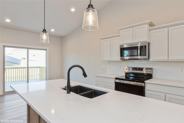 kitchen with hanging light fixtures, stainless steel appliances, backsplash, white cabinetry, and sink