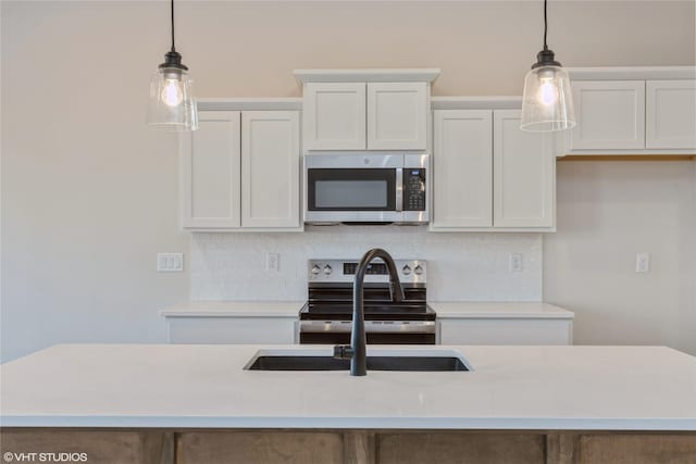 kitchen featuring decorative light fixtures, white cabinets, an island with sink, and appliances with stainless steel finishes