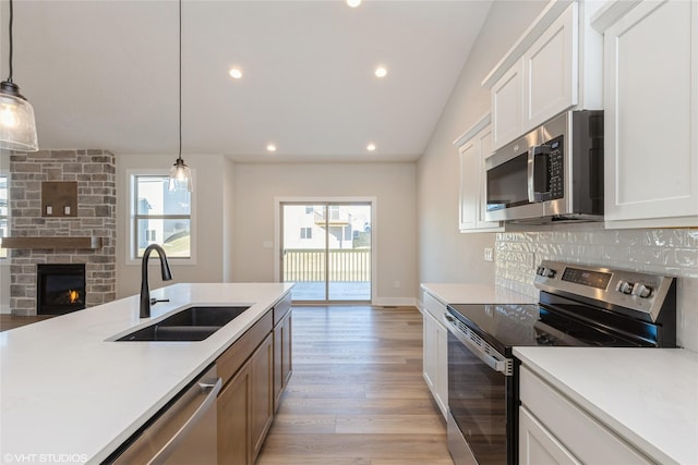 kitchen featuring stainless steel appliances, white cabinets, and pendant lighting