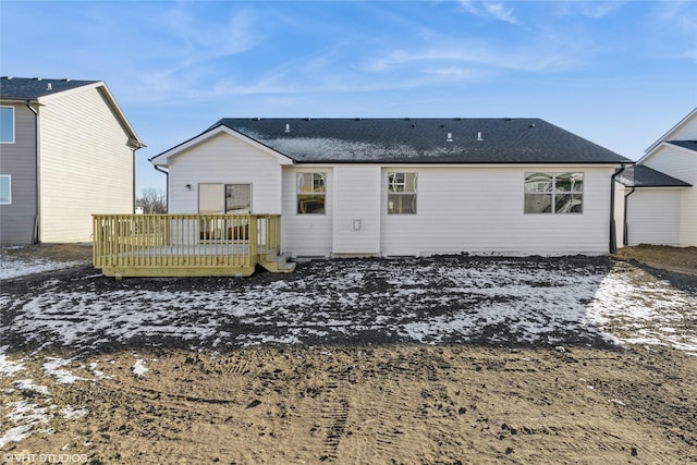 snow covered back of property with a wooden deck