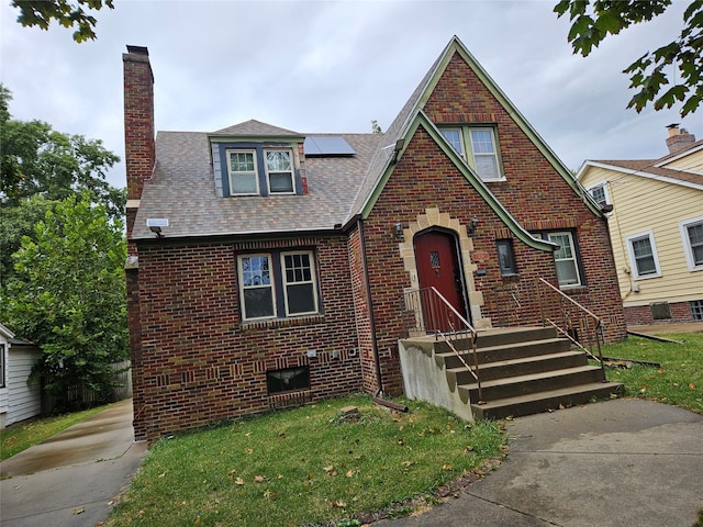 tudor-style house with a front yard and solar panels