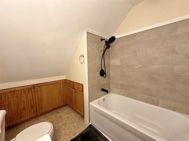 bathroom with tiled shower / bath combo, lofted ceiling, and toilet