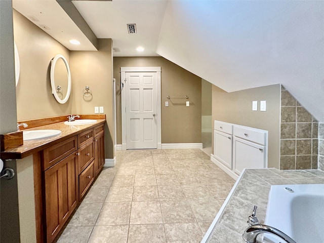 bathroom with tile patterned floors, vaulted ceiling, vanity, and a bathtub