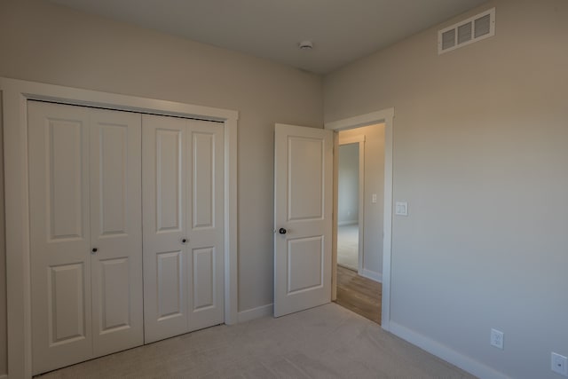 unfurnished bedroom with light colored carpet and a closet