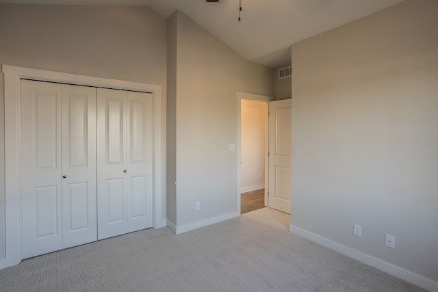 unfurnished bedroom with vaulted ceiling, light carpet, and a closet