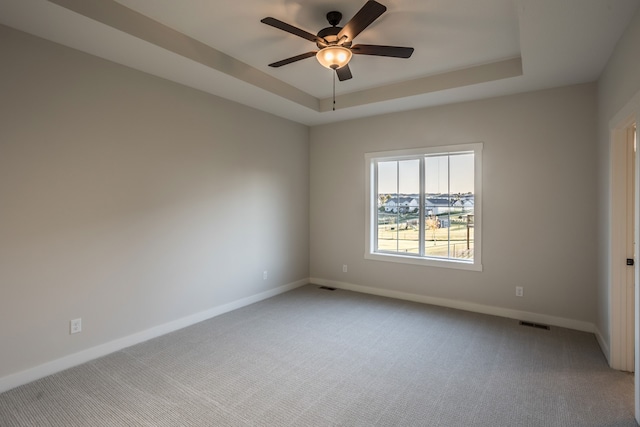 carpeted empty room featuring a raised ceiling and ceiling fan